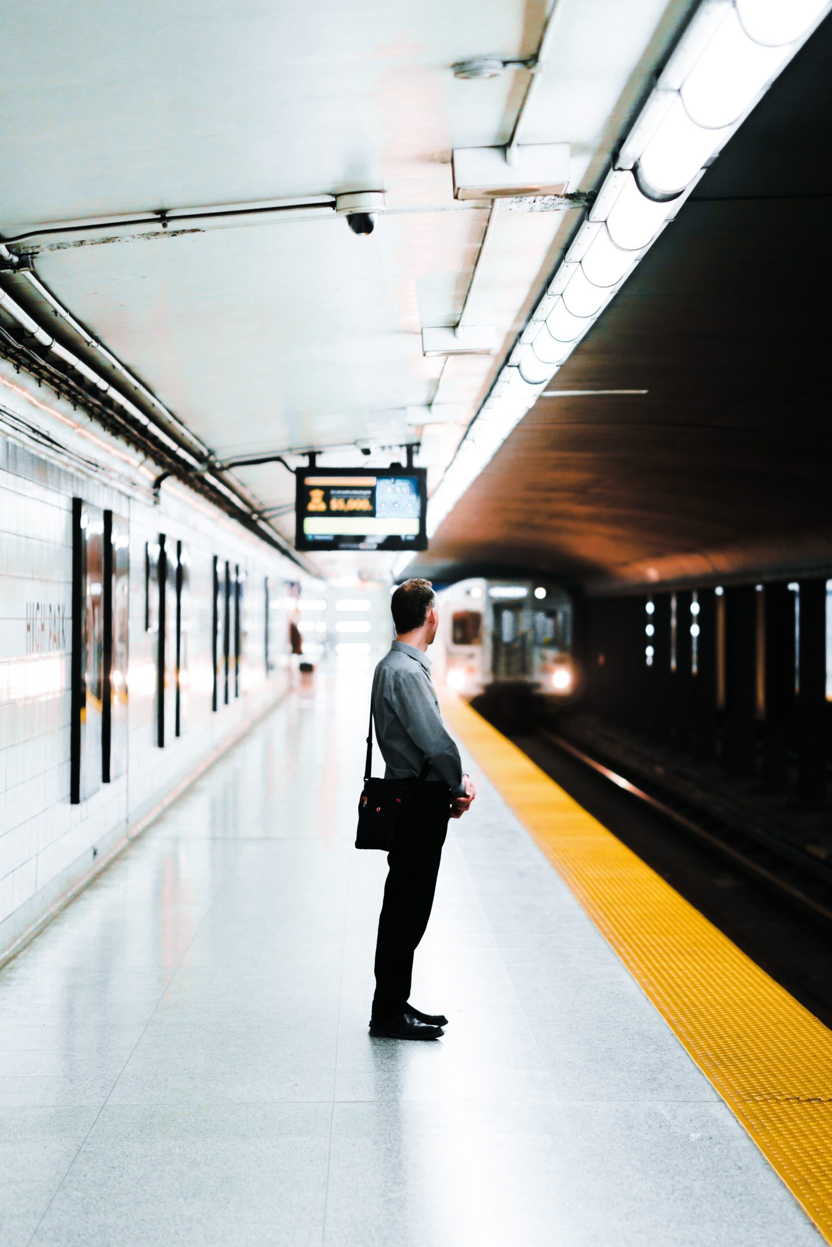 Un homme attend un train sur un quai lors de ses déplacements domicile-travail.