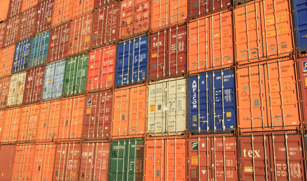 Many freight containers are stacked together in a warehouse.