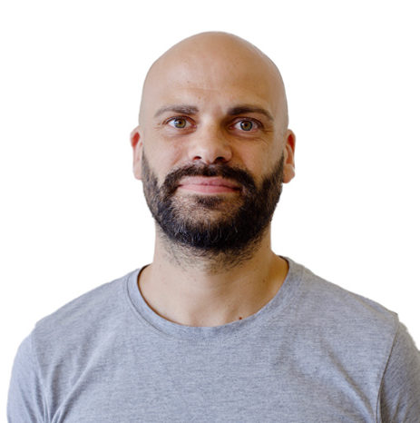 Un homme chauve avec une barbe est debout devant un fond blanc lors d'un évènement ou webinaire.