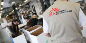 Un homme en gilet charge des cartons dans un entrepôt de MSF Logistique.