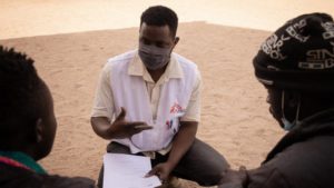 Un homme en chemise blanche discute avec un groupe de personnes au centre opérationnel MSF de Genève.