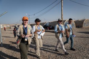 A group of nonviolent peaceforce walking in front of tents.