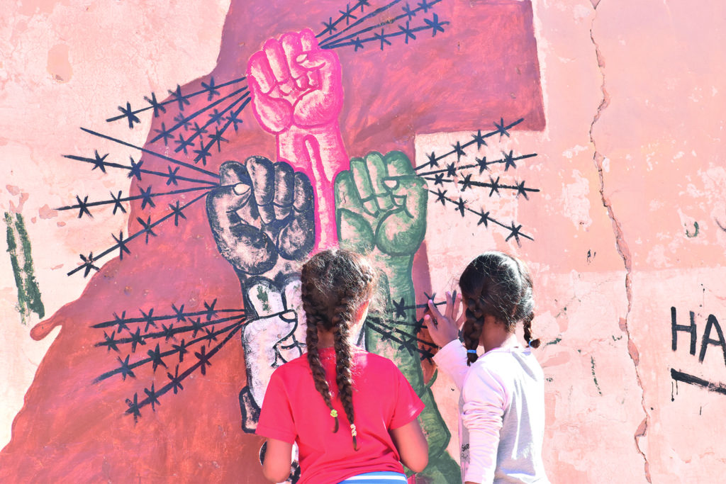 Deux filles peignant un mur avec du fil de fer barbelé.
