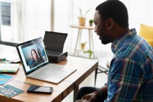 A man is teleworking at a desk with a laptop.