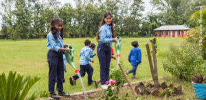 A group of children supported by the terre des hommes foundation are watering plants in a garden.