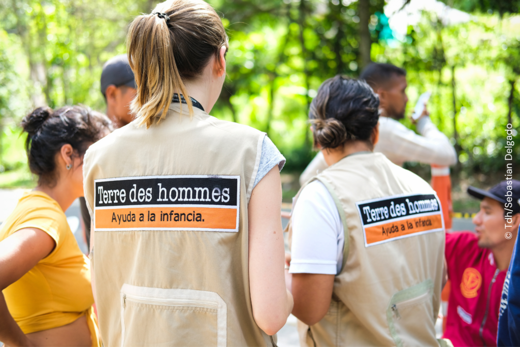 A group of people standing around in vests representing the terre des hommes foundation.