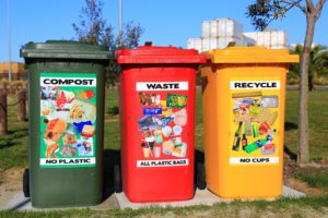 Trois poubelles rouges, jaunes et vertes pour écogestes au bureau.