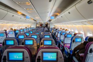 The interior of an airplane with a large number of monitors available for passengers in economy class tickets only.