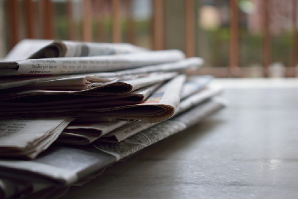 A stack of newspapers containing news articles on a table.
