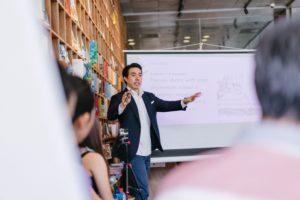 A man giving a presentation on target sectors to a group of people in a library.