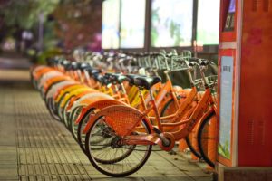 Une rangée de vélos orange garés sur un trottoir, faisant la promotion des écogestes au bureau et encourageant l'organisation.