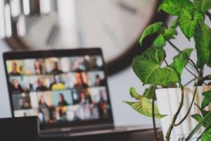 A laptop with a group of people on it engaged in online meetings.