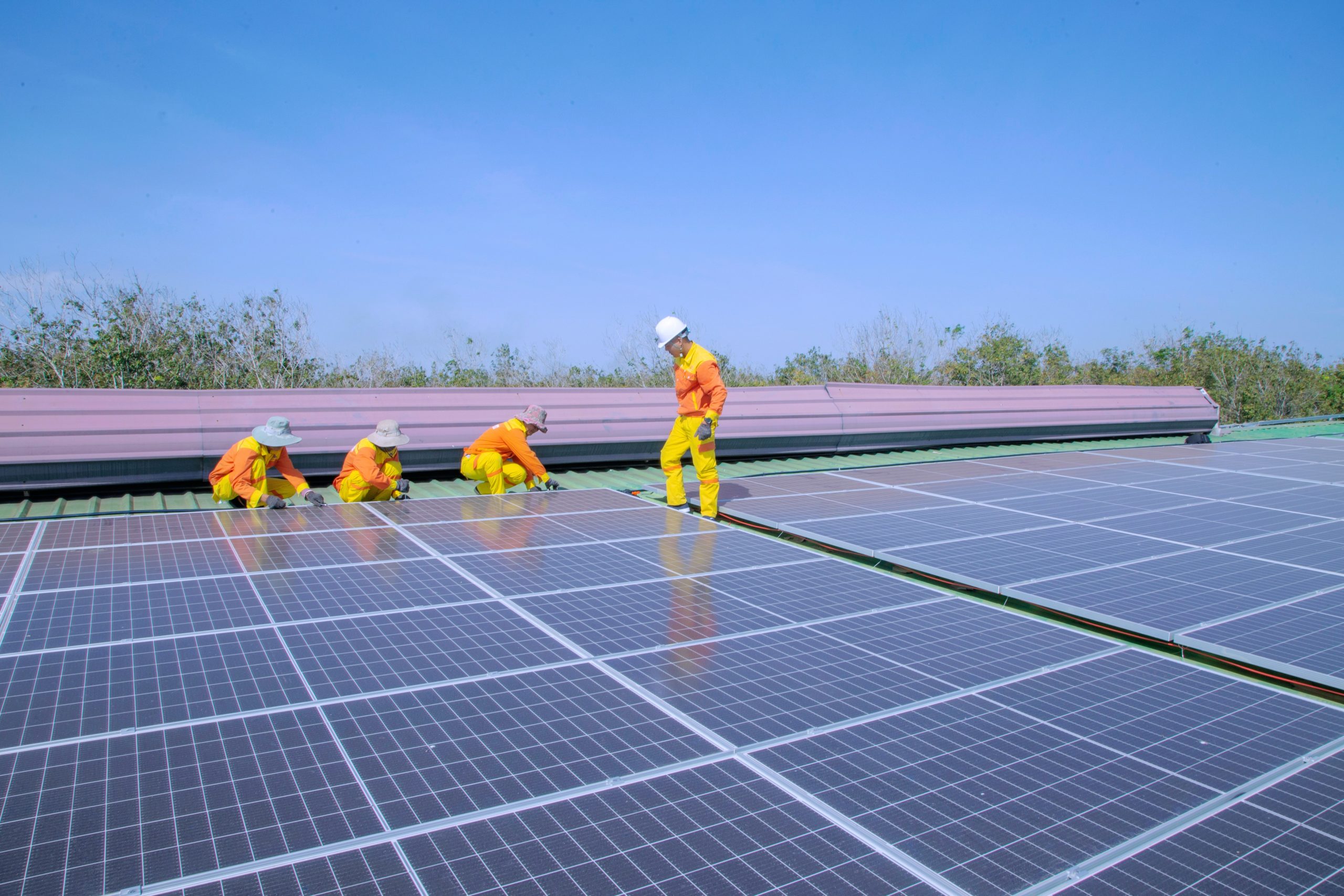 A team of workers is installing a solar panel on a building, harnessing renewable energy.