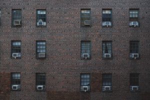 Un bâtiment en briques avec des climatiseurs aux fenêtres.